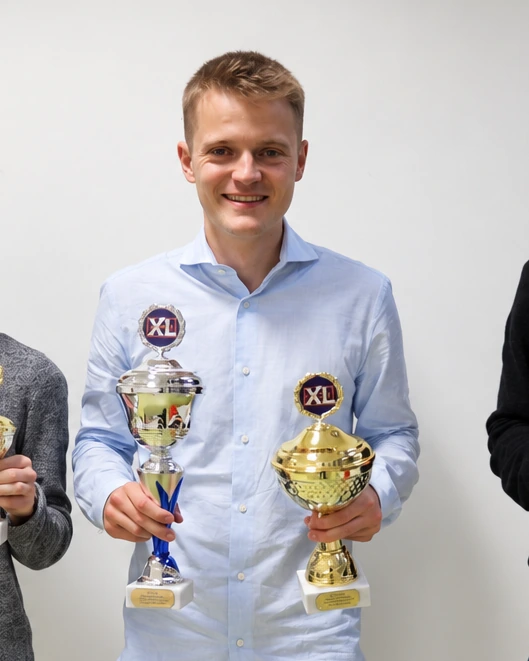 Bastian holding two trophies at a memory competition